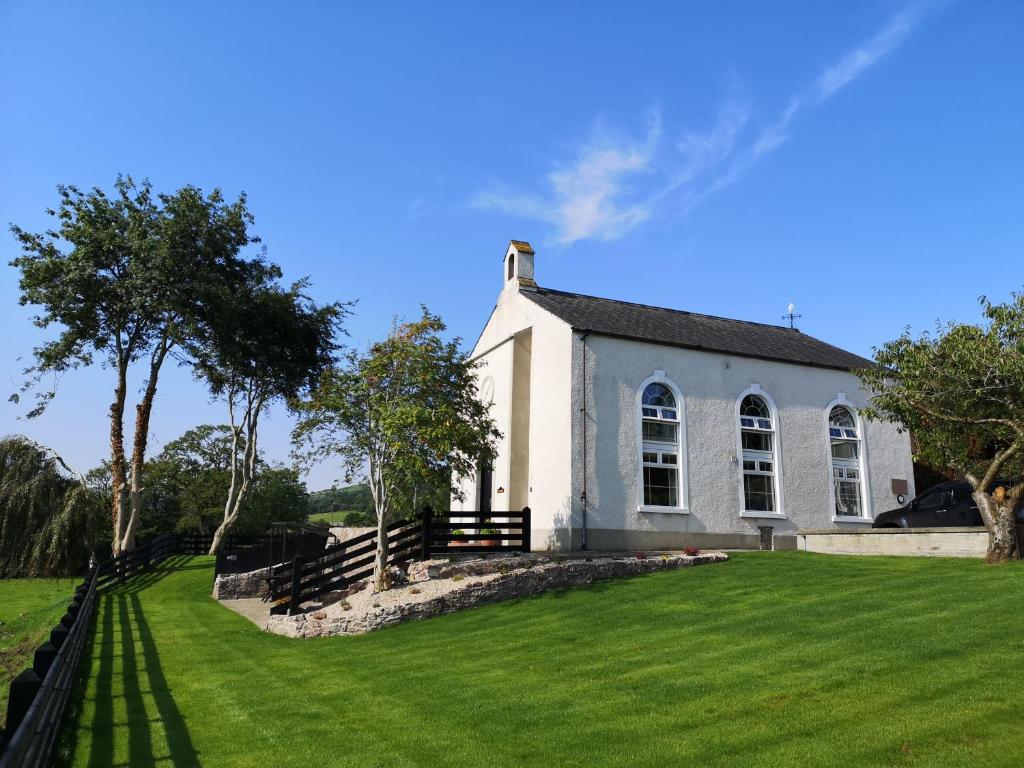 KnocknacarryMullarts Church -The Glenann Apartment的前面有一个草地庭院的白色教堂