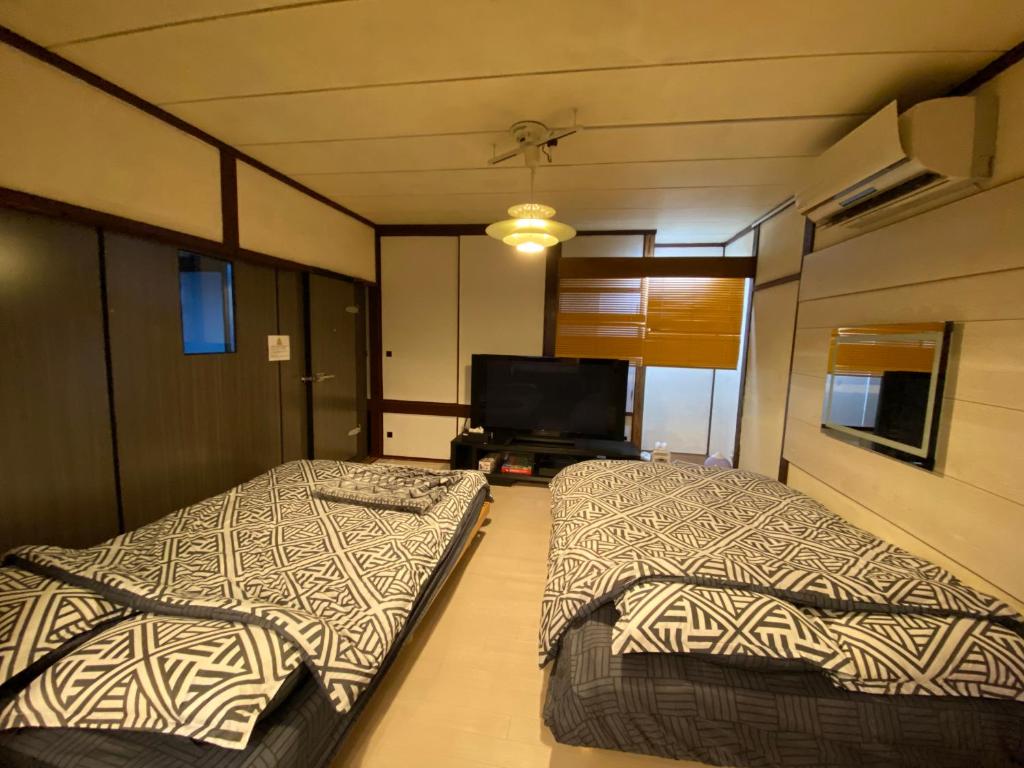 札幌札幌ドーム前ハウス Sapporodome front house的配有平面电视的客房内的两张床
