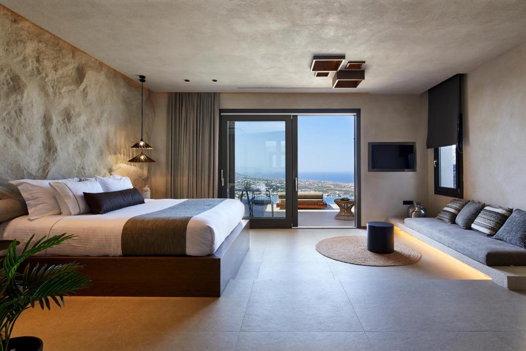 皮尔戈斯North Santorini - A Luxury Spa Hotel的一间卧室配有一张床、一张沙发和一台电视。