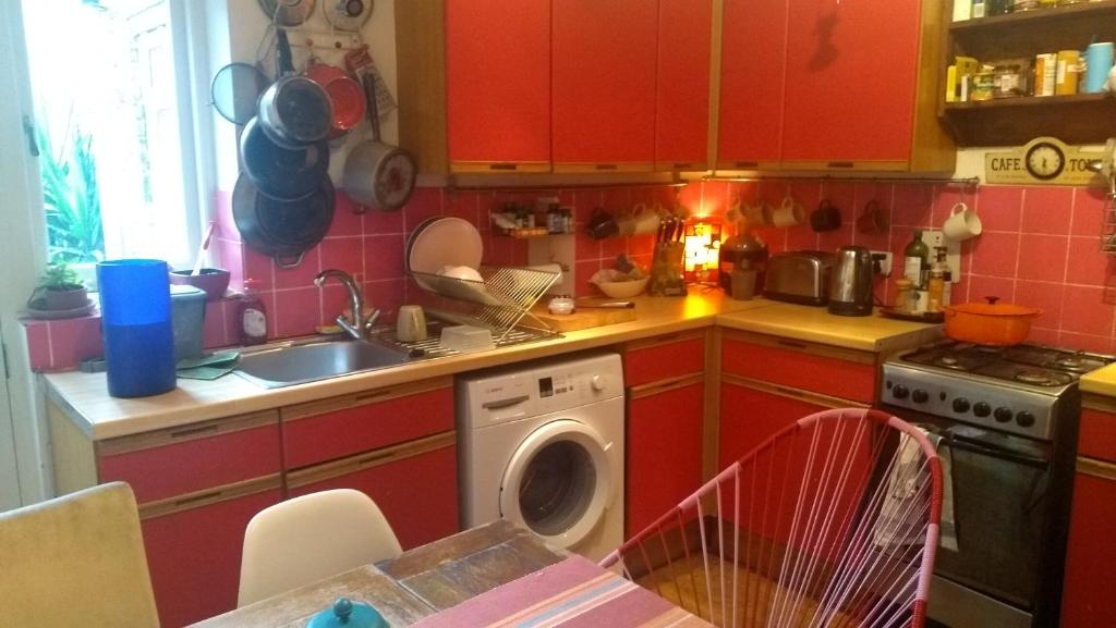 伦敦Homey, warm & welcoming room.的一间带红色橱柜和洗衣机的厨房