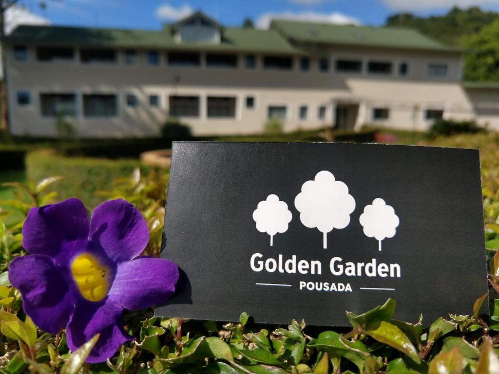 卡尚布Pousada Golden Garden的花园花园标志旁的紫色花