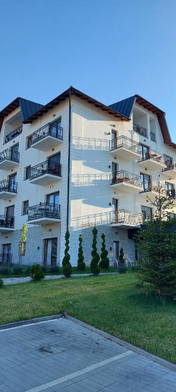兹拉蒂博尔Apartman Aura Hills Zlatibor的一座大型白色公寓大楼,设有停车场