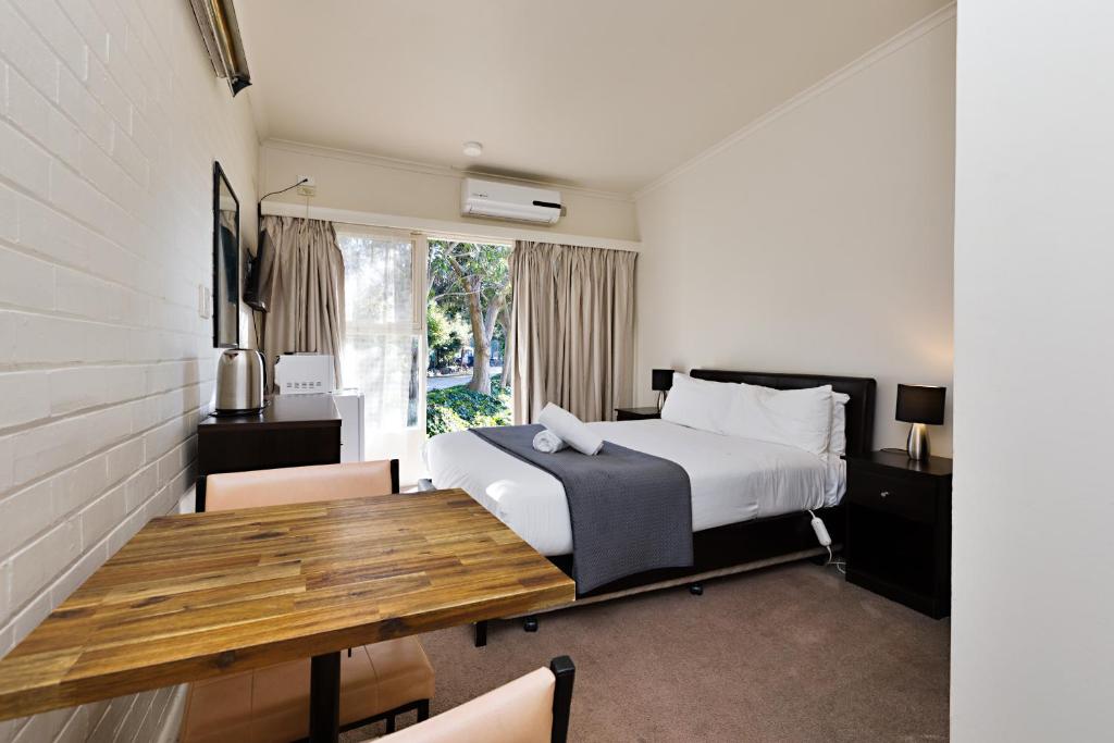 旺加拉塔园景汽车旅馆的一间卧室配有一张床和一张木桌