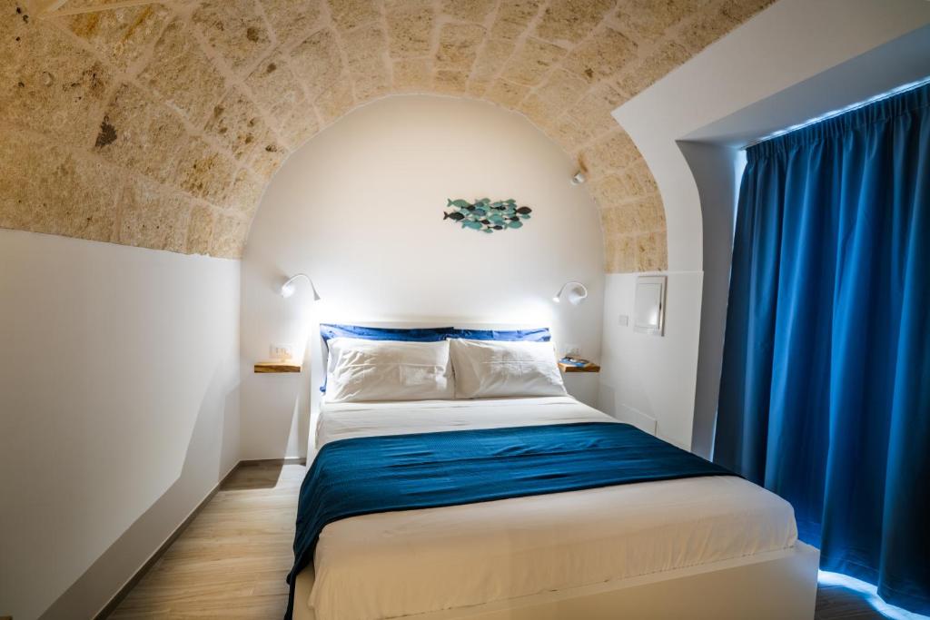 滨海波利尼亚诺Vico Blu的小房间,配有一张蓝色窗帘的床