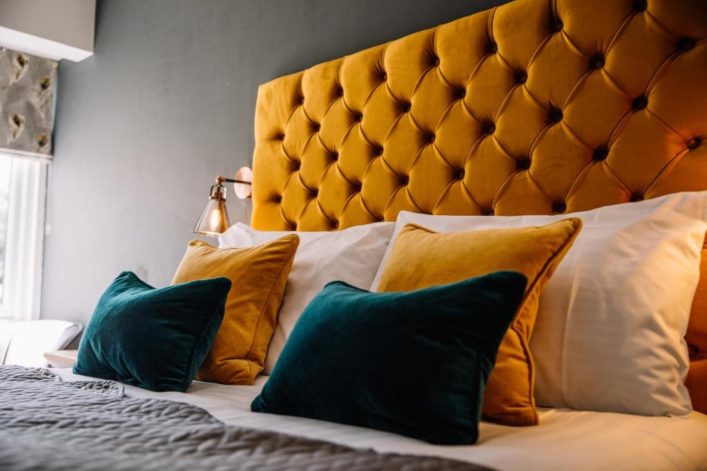 Crooklands克鲁克兰酒店的一间卧室配有一张大床,提供黄色和绿色的枕头