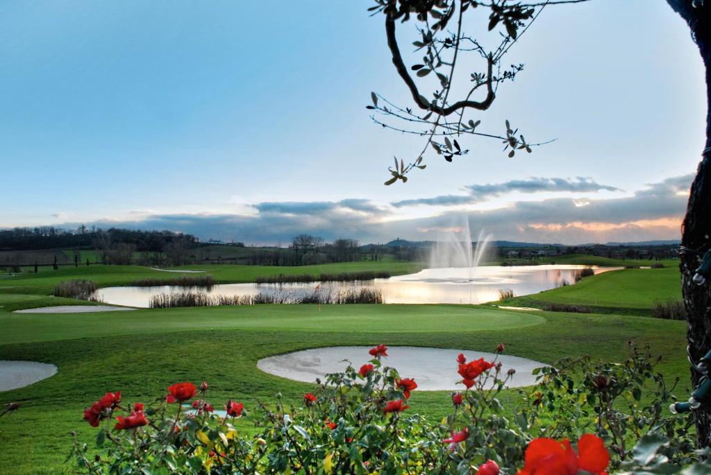波佐伦戈Garda Hotel San Vigilio Golf的享有带池塘和鲜花的高尔夫球场的景色