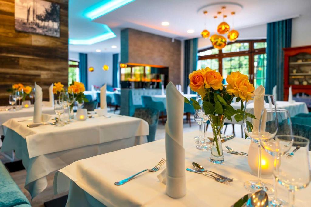 奥茨塞巴德·迪尔哈根布林克菲尔酒店的用餐室配有白色桌子和黄色鲜花