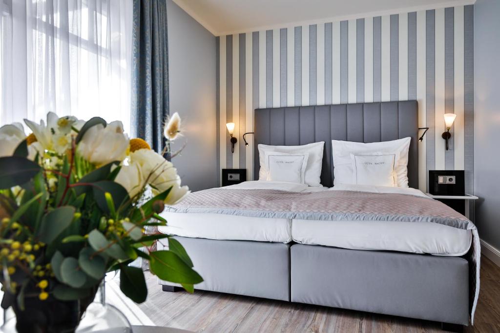 韦斯特兰Sylthotel Raffelhüschen Garni的卧室配有白色床和条纹墙