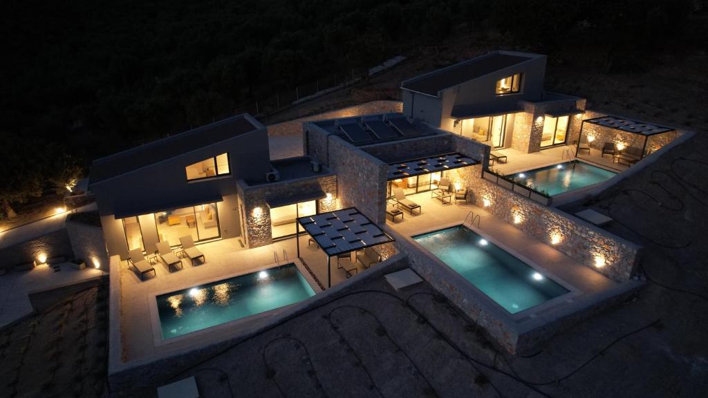 普洛马里翁DAELIA Villas的享有房子的空中景色,晚上设有两个游泳池