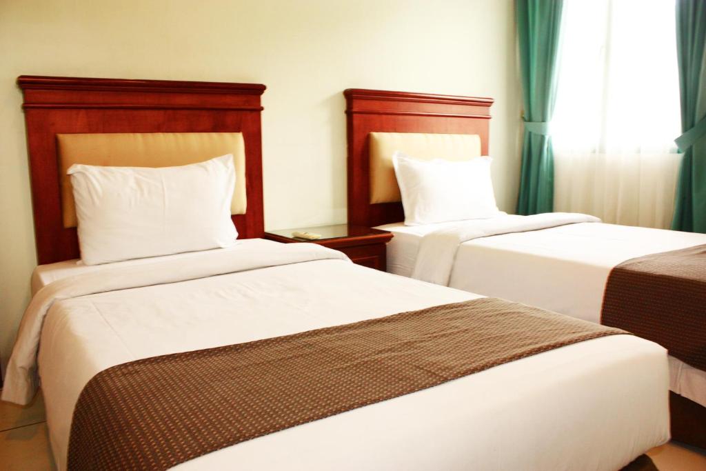 棉兰旅客套房服务式公寓的酒店客房设有两张床和窗户。