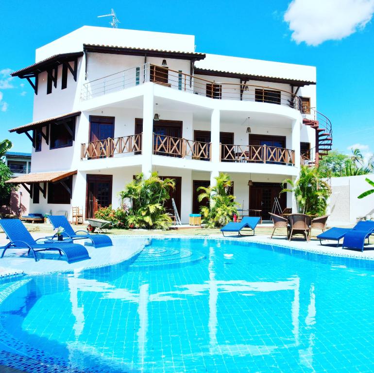 卡姆布库Hotel e Pousada Cumbuco Guesthouse的一座别墅,在一座建筑前设有一个游泳池