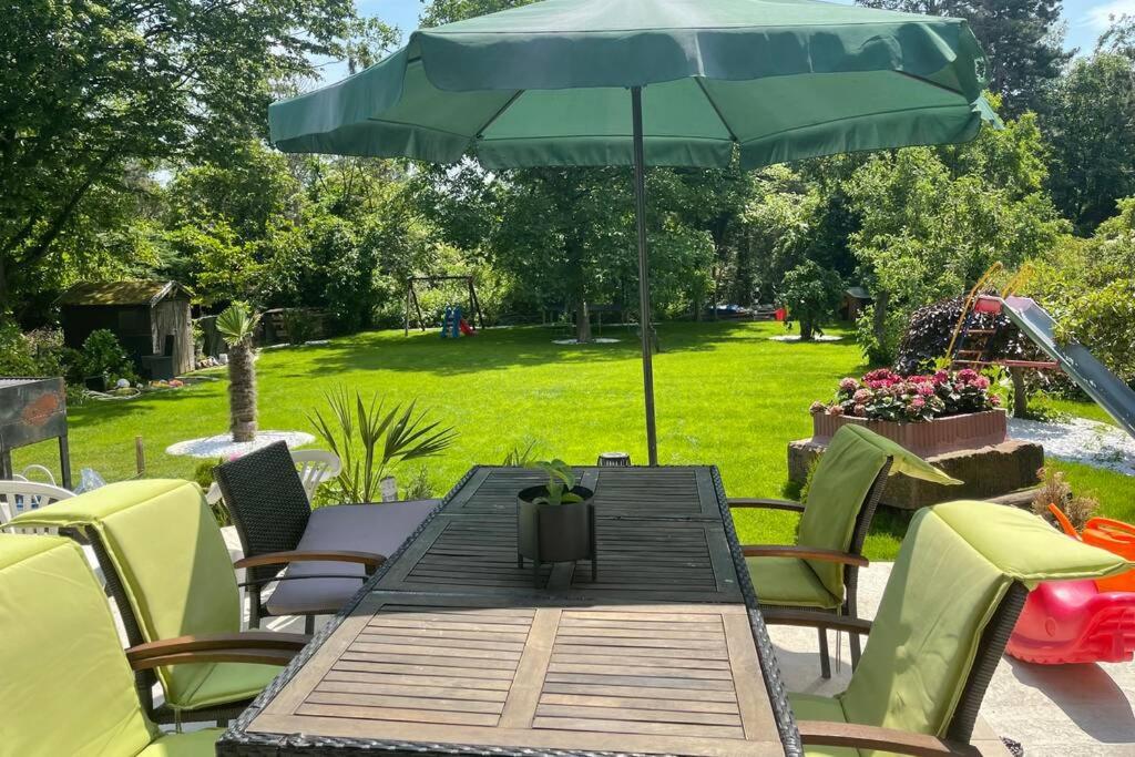 梅尔布施Wunderschöne Terrassenwohnung mit Blick ins Grüne!的一张带绿伞和椅子的木桌
