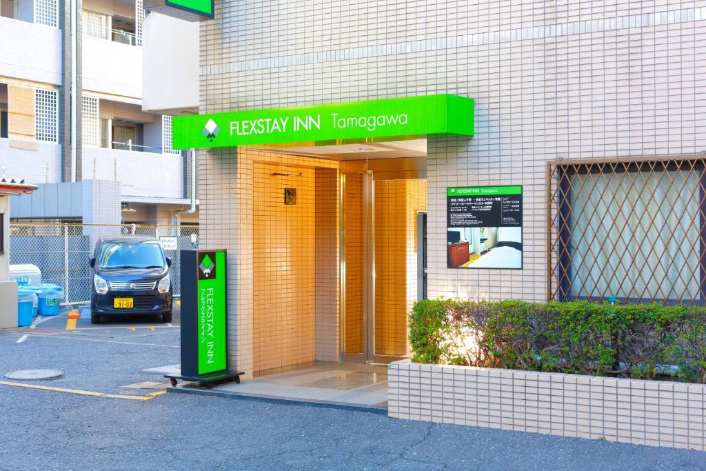 川崎FLEXSTAY 多摩川旅馆的建筑的入口,上面有绿色标志