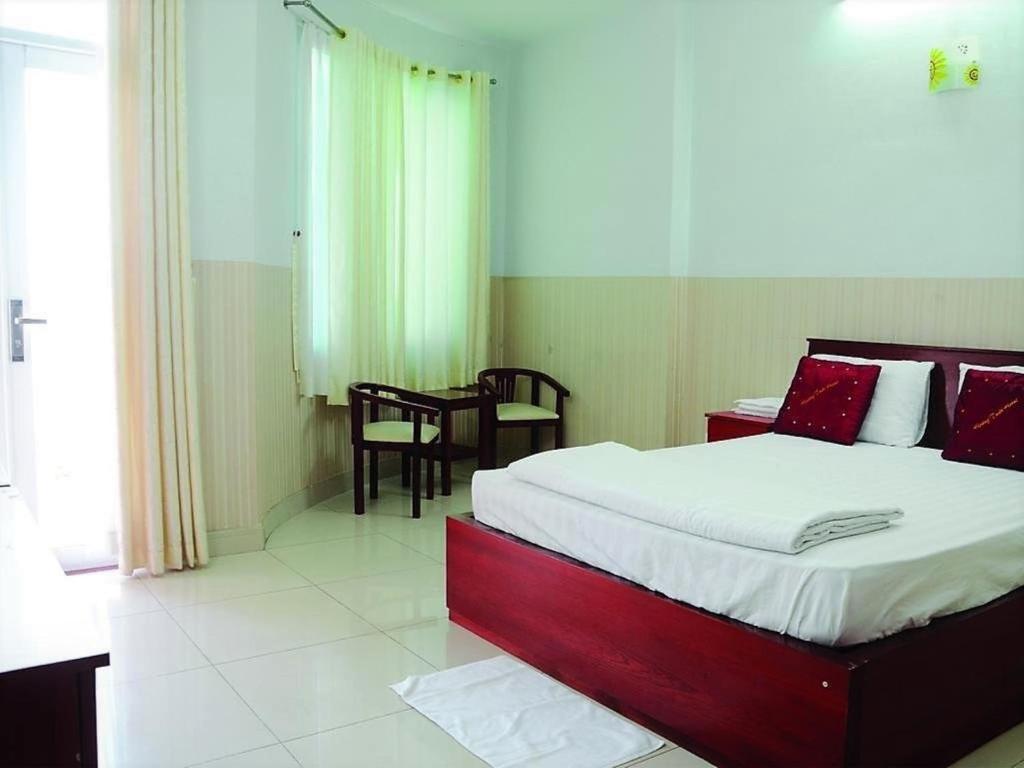 胡志明市Hoang Tuan Hotel的卧室配有一张床和一张桌子及椅子