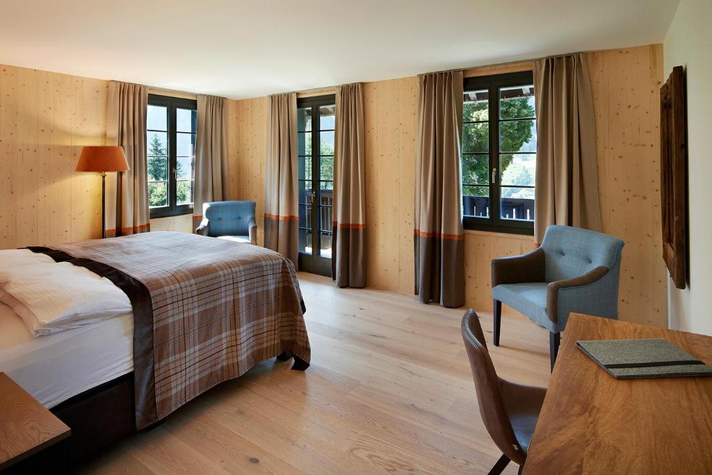 格林德尔瓦尔德Eiger View Alpine Lodge的酒店客房带一张床、一张桌子和椅子