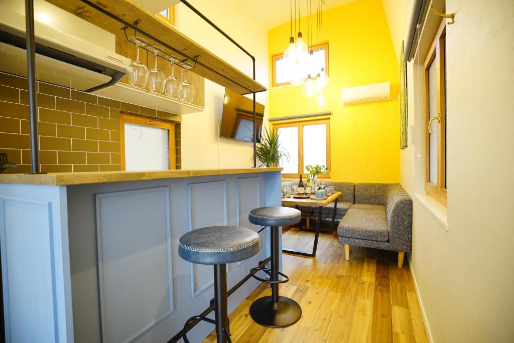 东京新築一軒家 東京ヴィラ リバーサイド平井的黄色墙壁的房间里,有凳子的酒吧