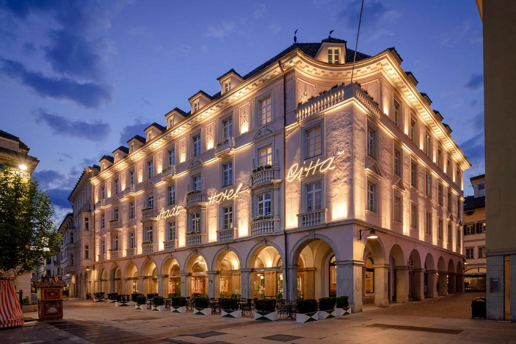博尔扎诺斯塔德特希塔酒店的一座白色的大建筑,灯火通明