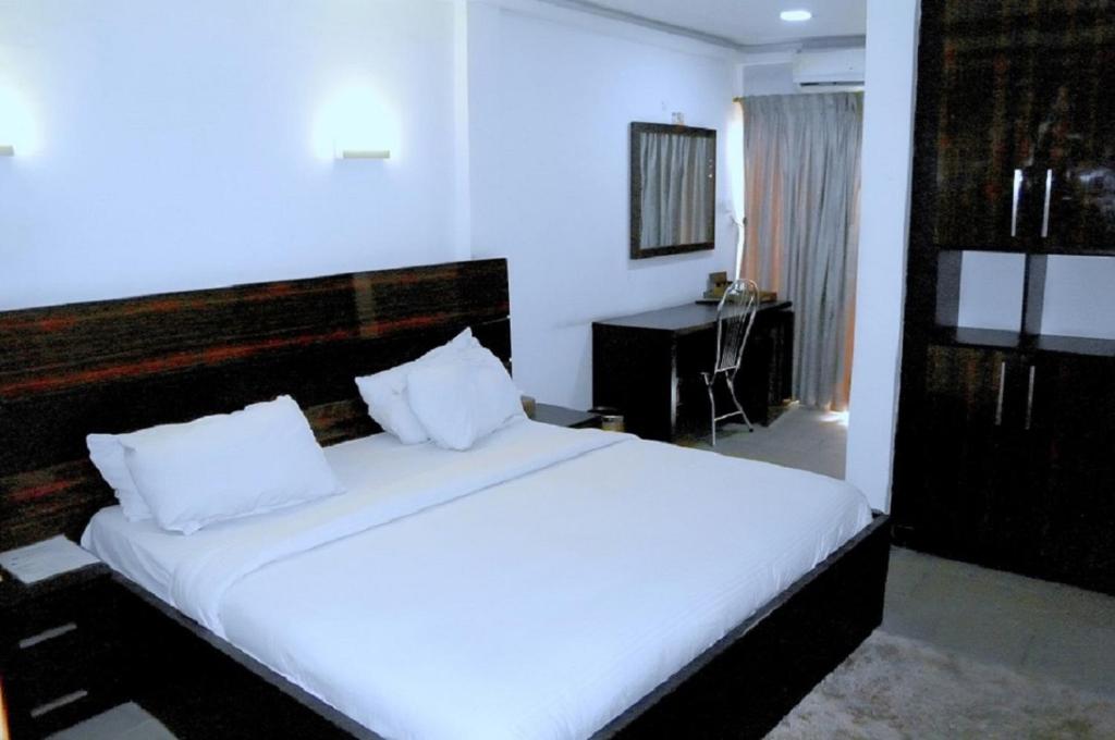 哈科特港Park Hotels的一间卧室配有一张带白色床单的大床和一张书桌