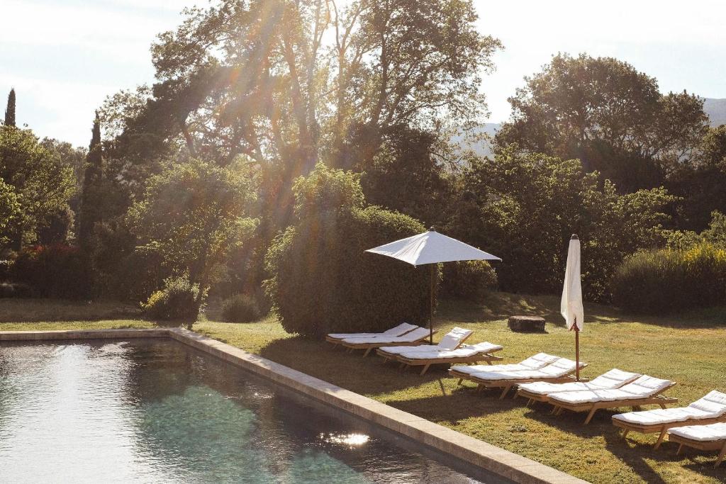 卢马罕Le Galinier, Lourmarin, an authentic Beaumier Guesthouse的一个带躺椅和遮阳伞的游泳池以及游泳池