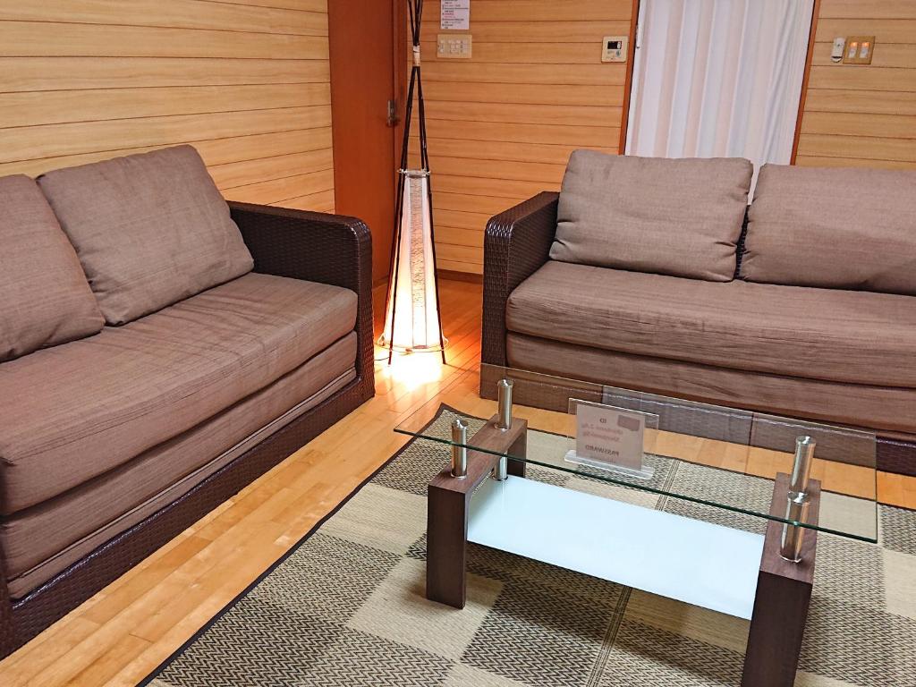 备濑新富的客厅配有两张沙发和一张玻璃桌