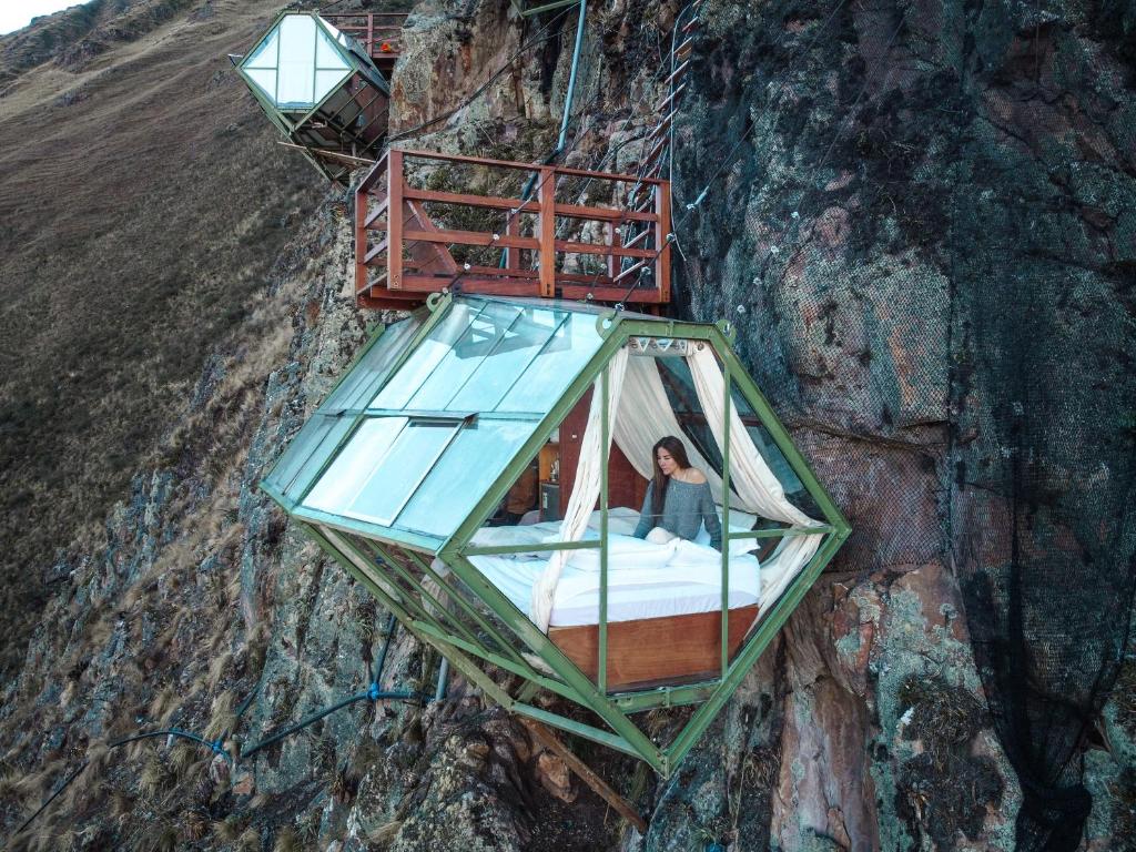 奥兰太坦波Vertical Sky Luxury Suites的女人在山上的玻璃房子里