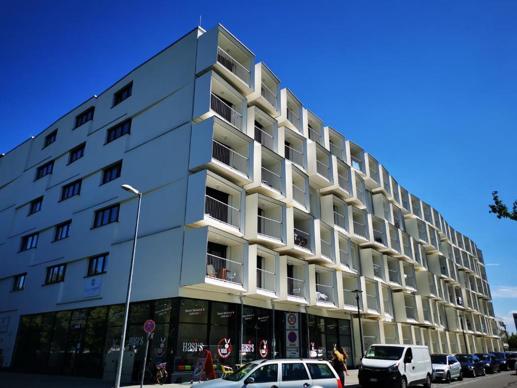 慕尼黑Top-Apartment a.d. Messe的一座白色的大建筑,前面有汽车停放