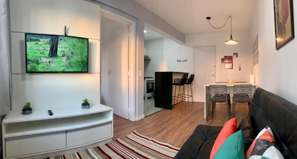 库里提巴707- Apartamento Encantador, amplo e decorado, quarto, sala, cozinha, mobiliario moderno, cozinha completa com utensílios , Excelente vista da cidade e localização privelegiada no bairro Bigorrilho的客厅配有沙发和墙上的电视