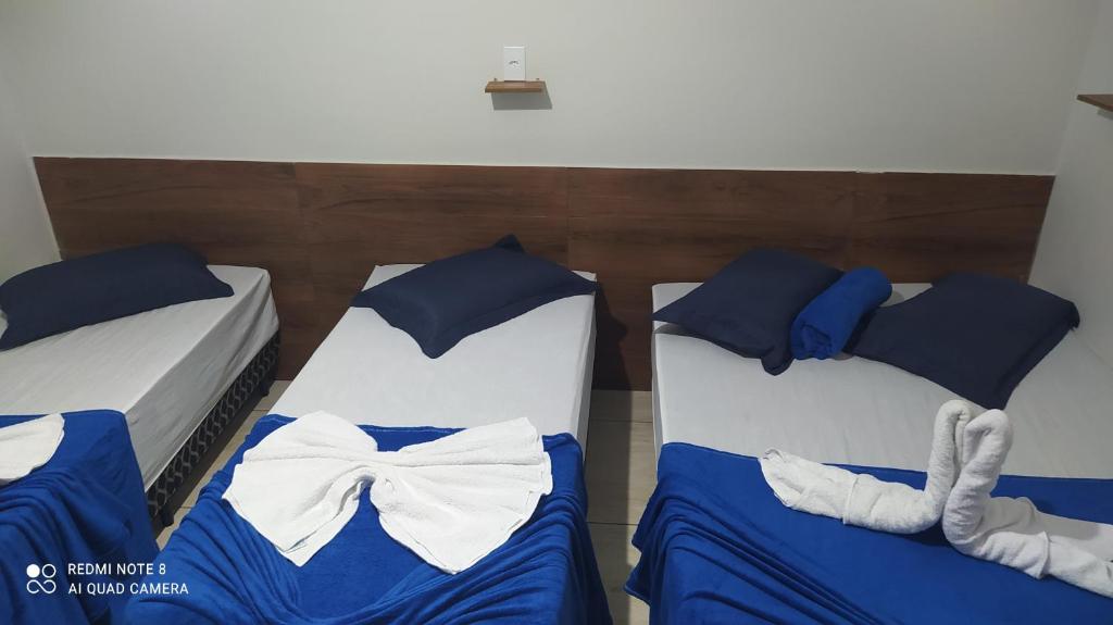 阿帕雷西达Pousada Quarto com frigobar,ar e garagem gratuita的两张带蓝色床单和弓领带的床
