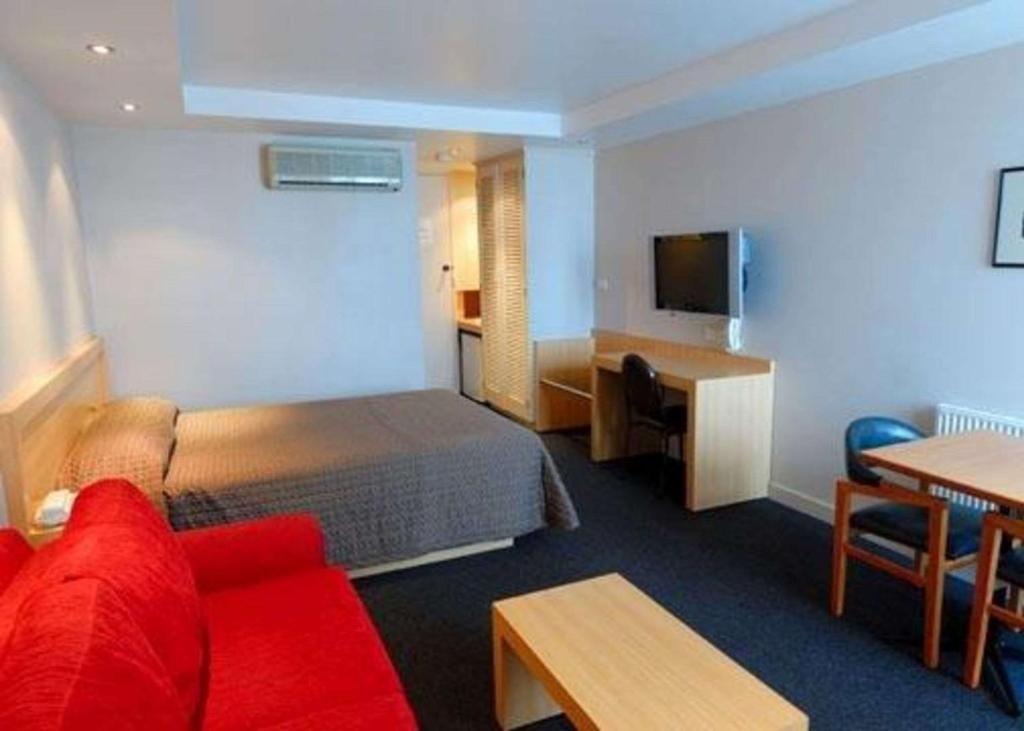 波特兰Richmond Henty Hotel的酒店客房配有红色的沙发和床。