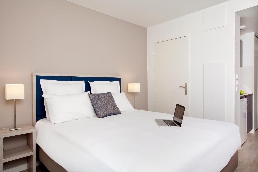 巴涅奥莱Séjours & Affaires Paris Bagnolet的一间卧室配有一张白色的床,上面有笔记本电脑