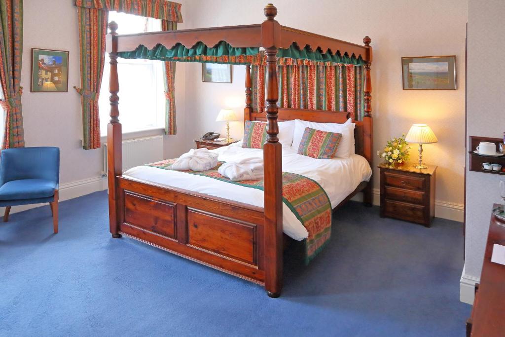 惠特比萨克森维尔酒店的一间卧室配有天蓬床和蓝椅
