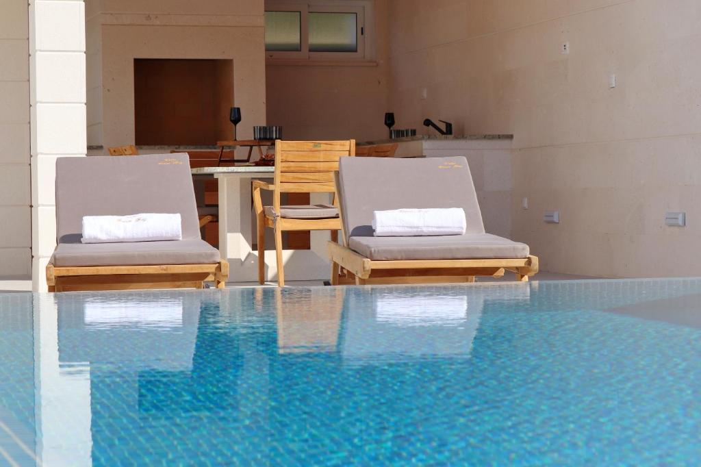 尼亚卢卡Villa Green Bay Apartments的游泳池旁的两把椅子