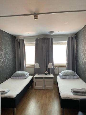 赫尔辛堡Helsingborgs Vandrarhem, Helsingborg Hostel的一间卧室配有两张床、一张桌子和两个窗户。