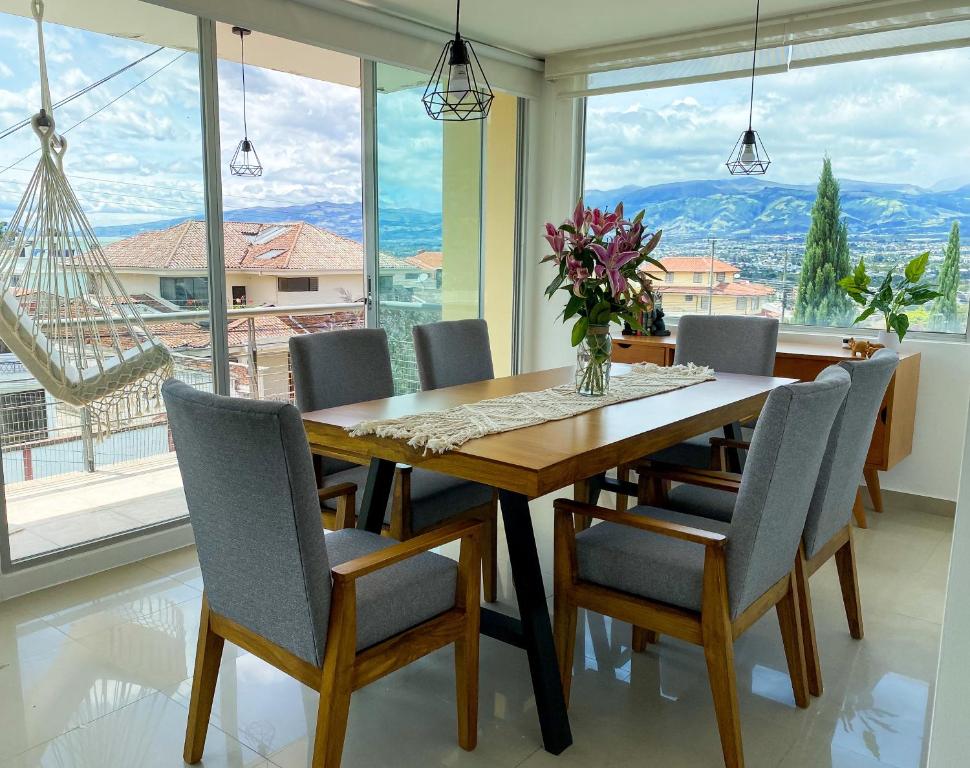 基多HERMOSO DEPARTAMENTO CON INCREIBLES VISTAS CUMBAYA的一间带桌椅和大窗户的用餐室