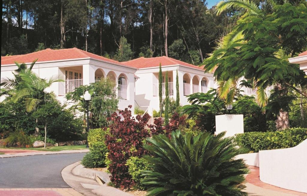 黄金海岸皇家森林度假村的前面有树木和植物的白色房子