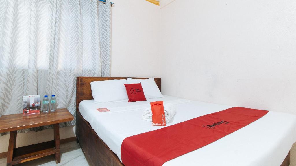ZambalesRedDoorz Hostel @Megans Paradisio Beach Resort的一间卧室配有两张带红色枕头和桌子的床