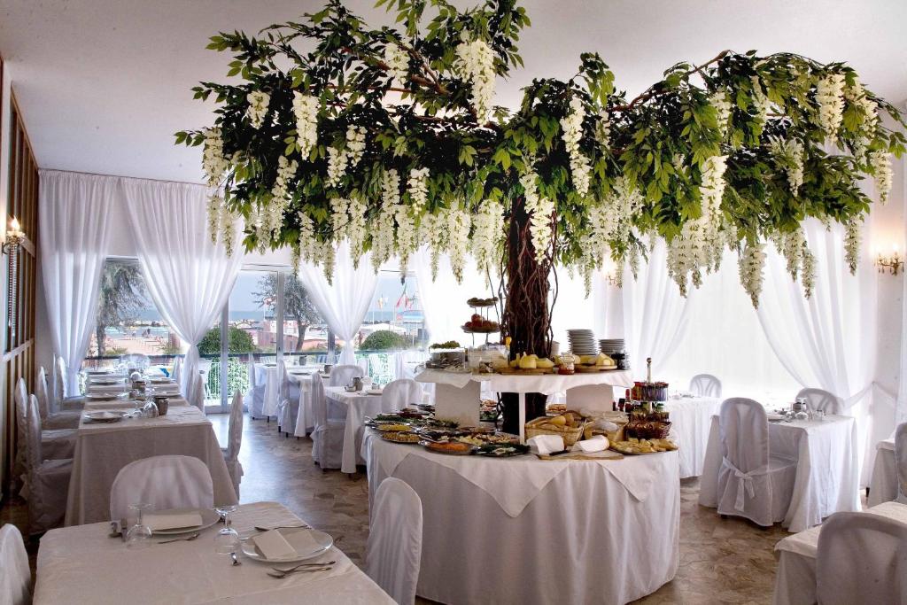 里米尼天堂酒店的一间设有白色桌子的房间,里面有一棵树