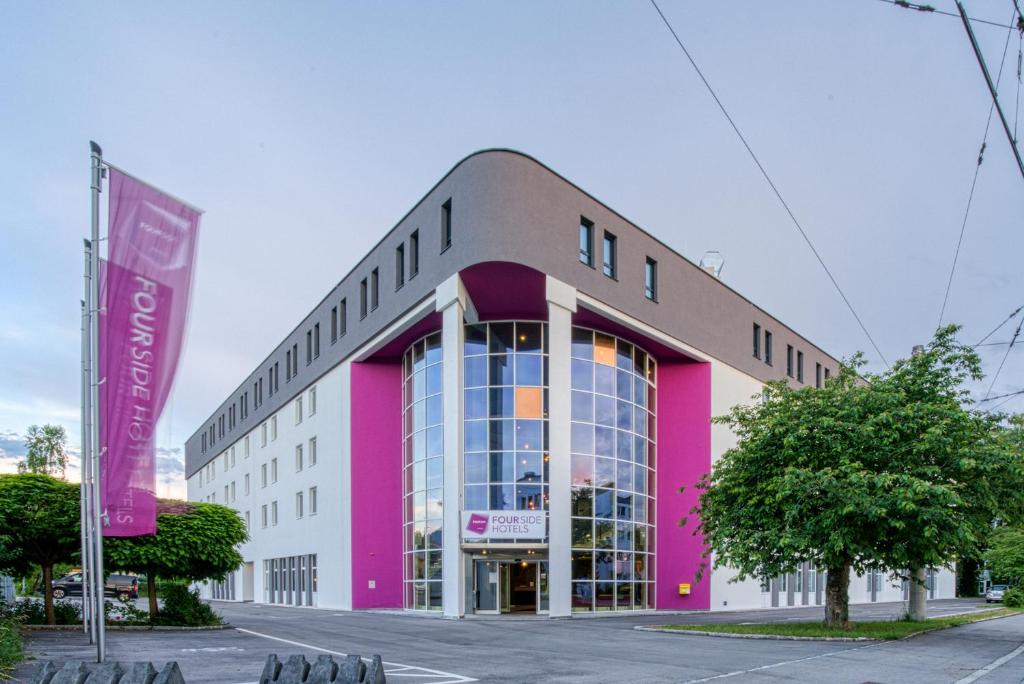 萨尔茨堡FourSide Hotel Salzburg的街道上的粉红色和白色建筑