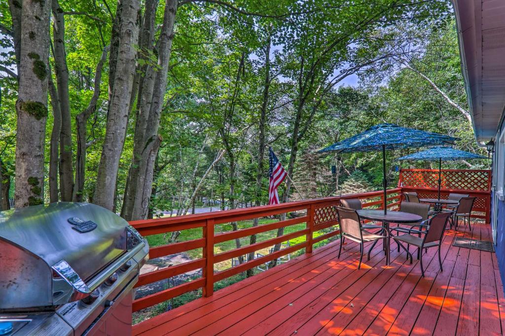 BlakesleeUpdated Blakeslee Cottage with Fire Pit and Deck!的木制甲板配有椅子、桌子和遮阳伞