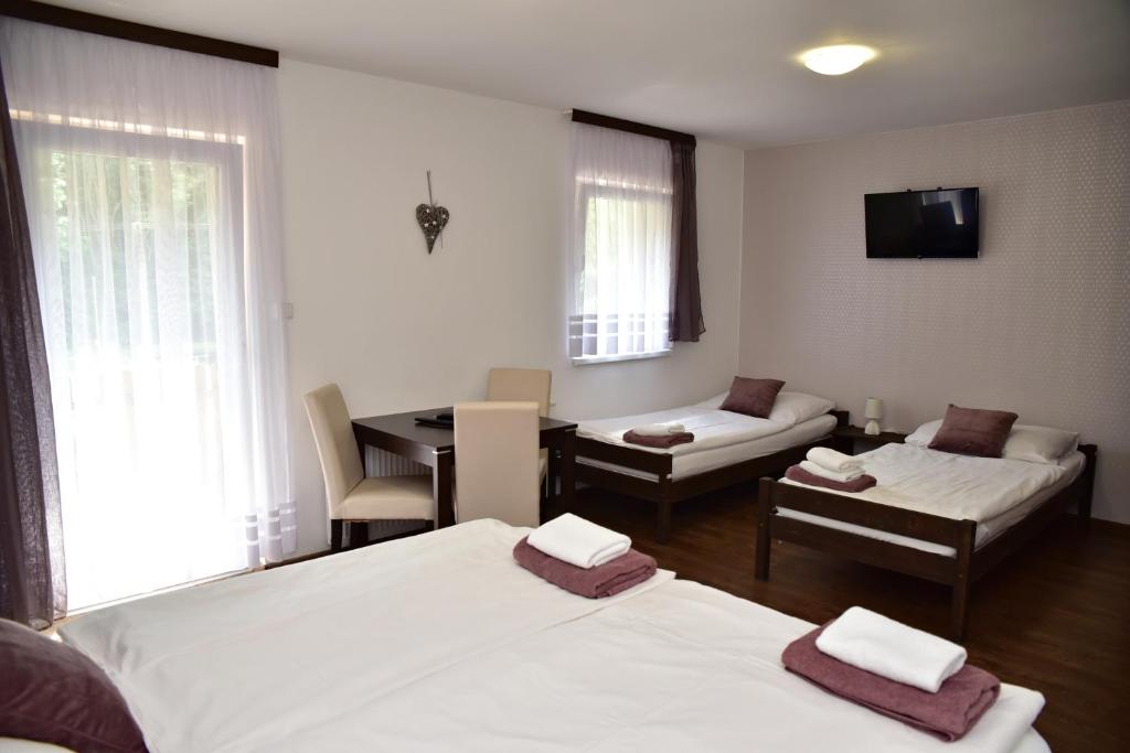 Mikulov v Krušných Horách克布旅馆的客房设有两张床、一张桌子和一张沙发。