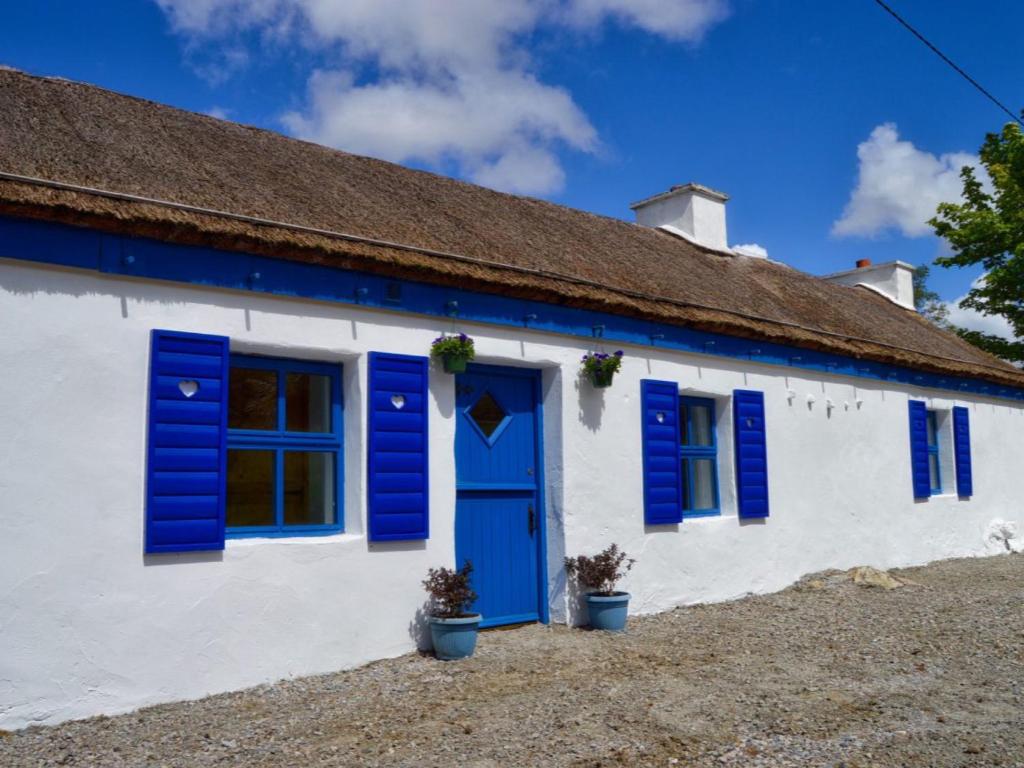 DoocharyBeautiful Thatched Adderwal Cottage Donegal的蓝色和白色的房子,设有蓝色百叶窗