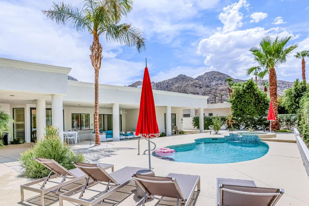 印第安维尔斯Luxury Estate in Indian Wells Country Club的一个带椅子的庭院和一个棕榈树游泳池