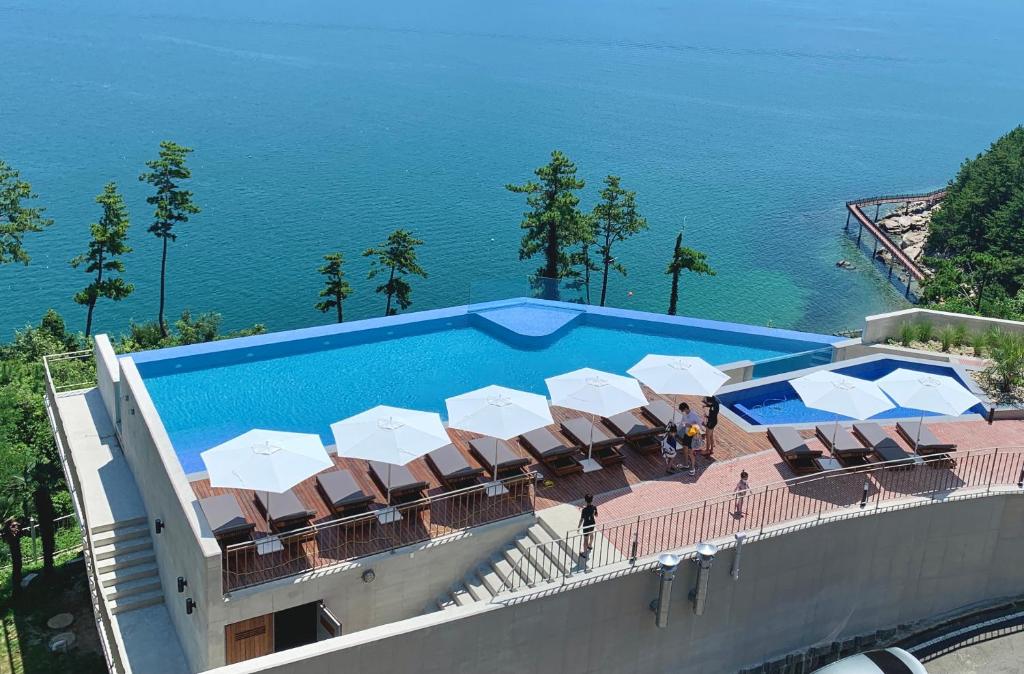 巨济Hotel SANG SANG的毗邻大海的带椅子和遮阳伞的游泳池