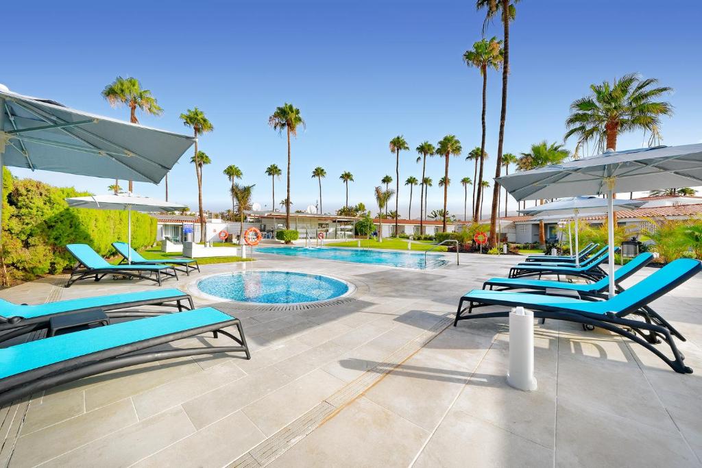 英格兰海滩普拉西娅洛格拉斯勒酒店的一个带蓝色躺椅的游泳池和一个游泳池