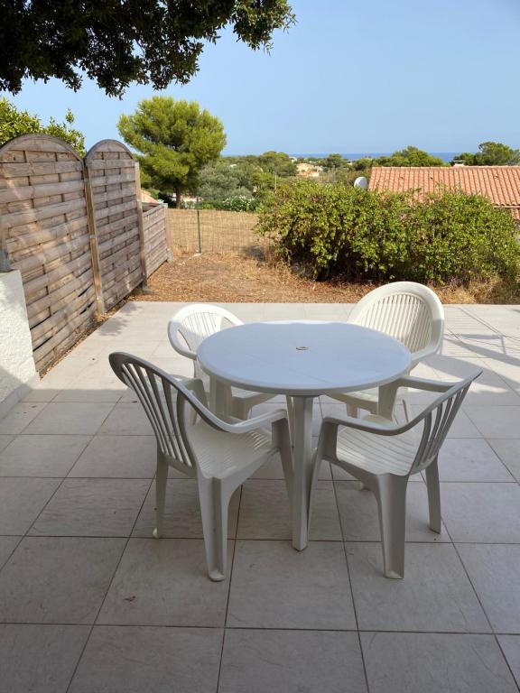 卢米奥Location 5 personnes Sant Ambroggio Cocody village的庭院里摆放着白色的桌椅