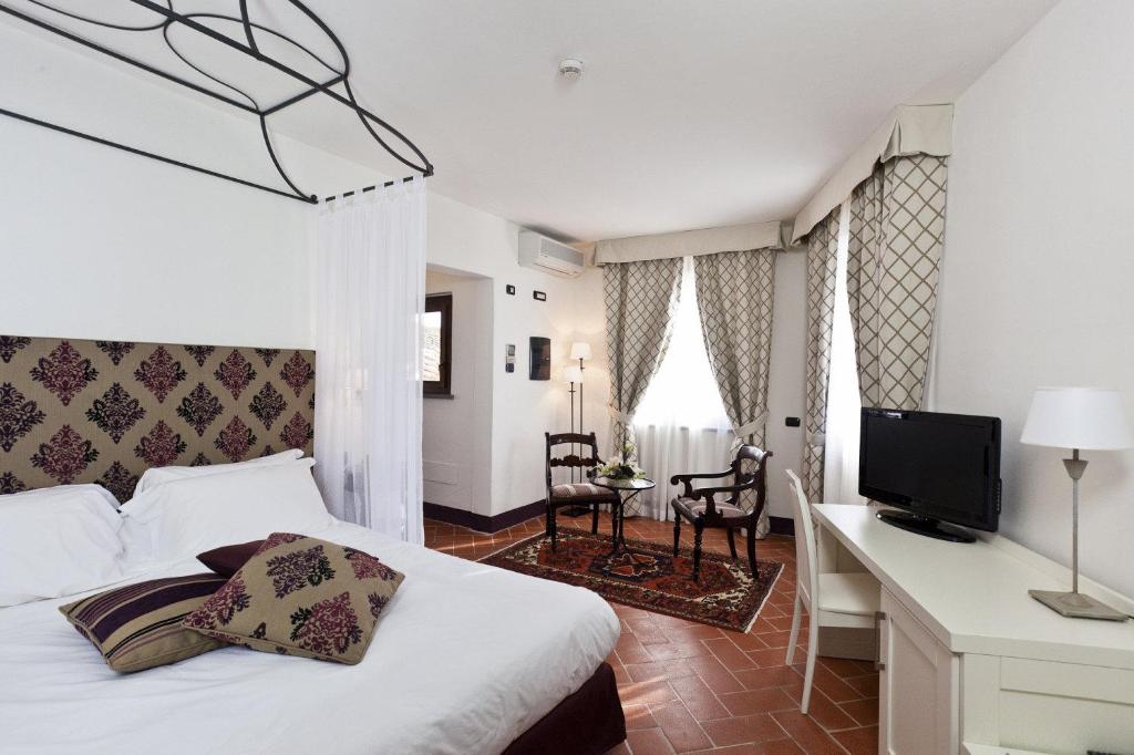 圣米尼亚托圣米尼亚托酒店的一间卧室配有一张床、一张书桌和一台电视