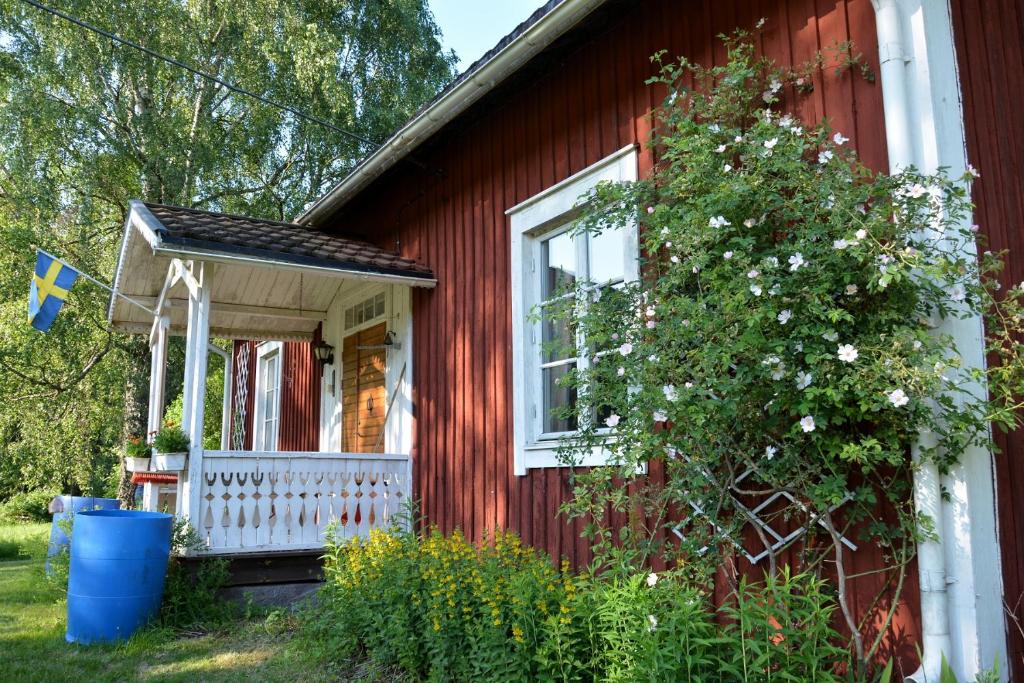 SurahammarLillstugan, södra Bergslagen的红色的房子,有白色的门廊和一棵树