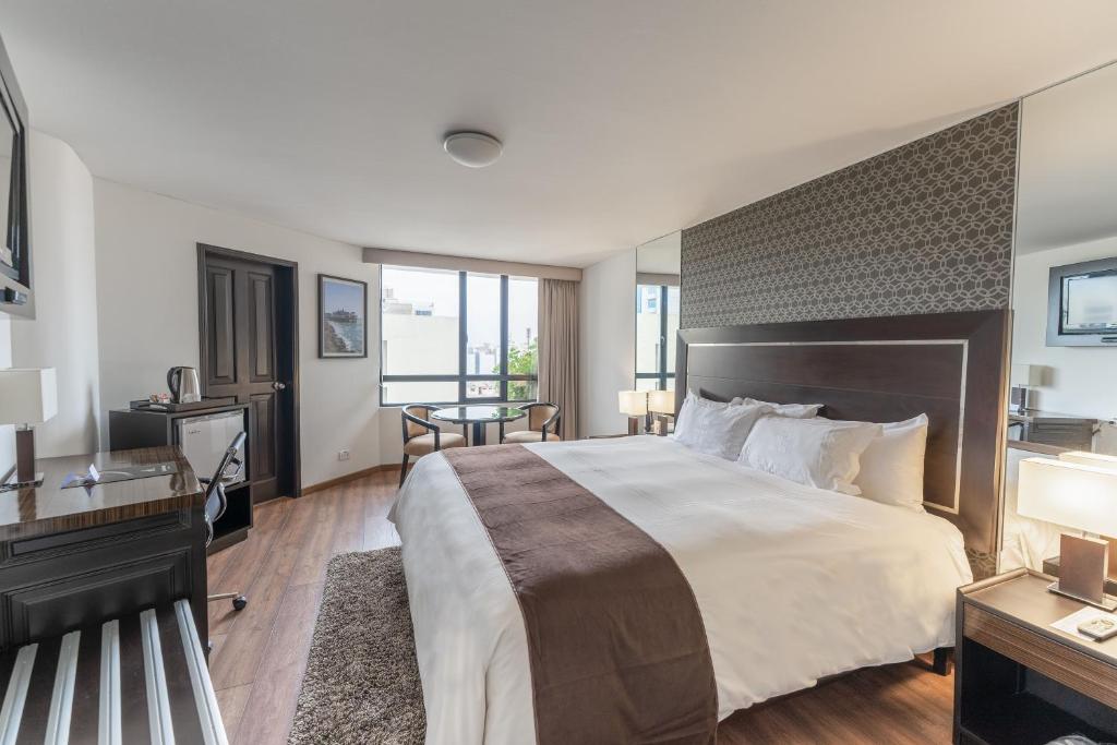 利马何塞安东尼奥行政酒店的酒店客房设有一张大床和一张书桌。