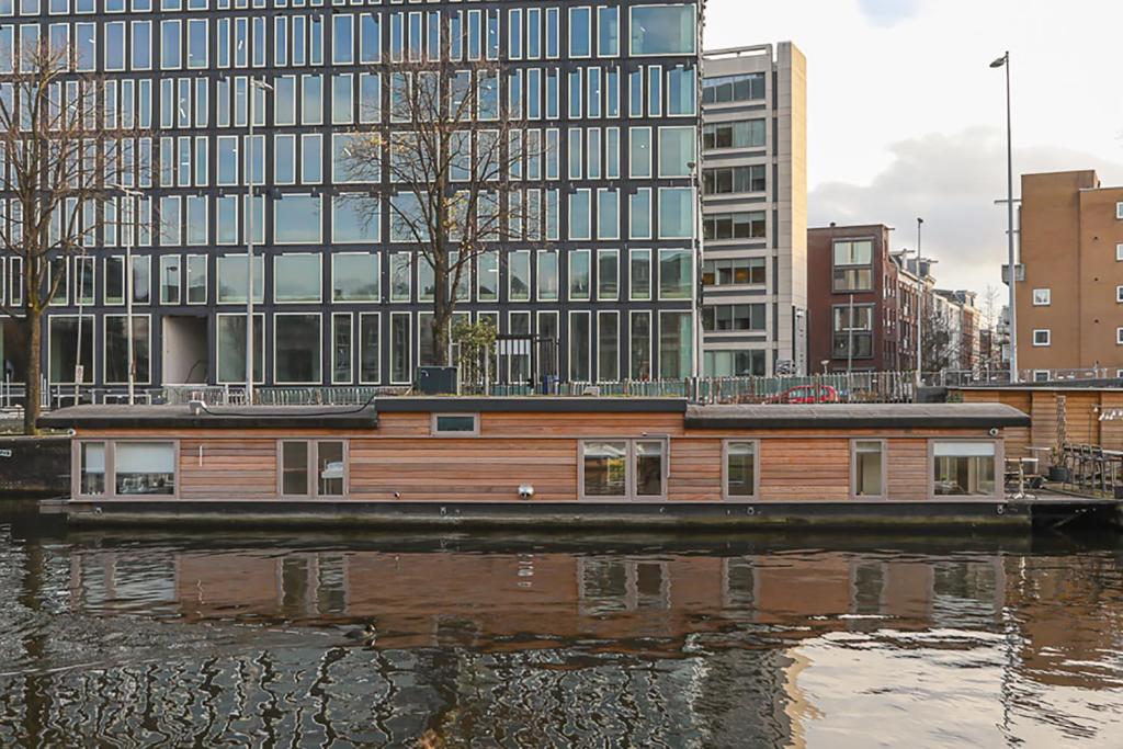 阿姆斯特丹HouseBoat next to AMSTEL的建筑物前的水面上船屋