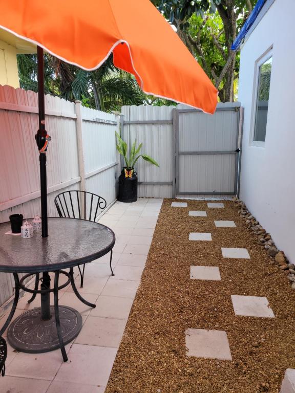 迈阿密Suite Life at Chez Mercedes的庭院配有桌子和橙色遮阳伞。